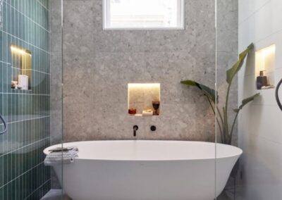 a bathroom with a white tub and green tiled walls.