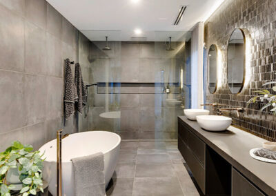 a modern bathroom with grey tiled walls, niche and a bathtub.