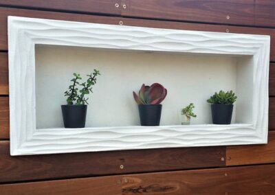 a white wall mounted rectangular niche with potted plants